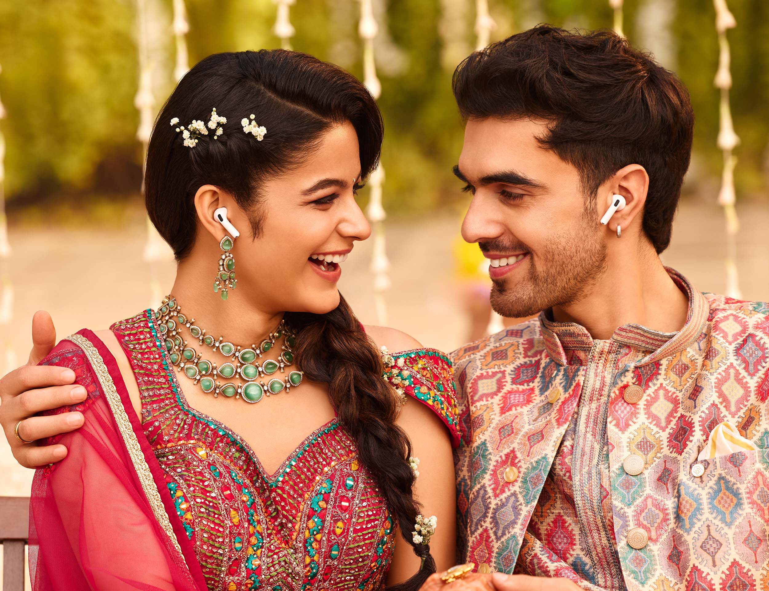 Smiling couple in vibrant traditional outfits enjoying candid pre-wedding photography with matching jewelry and accessories.